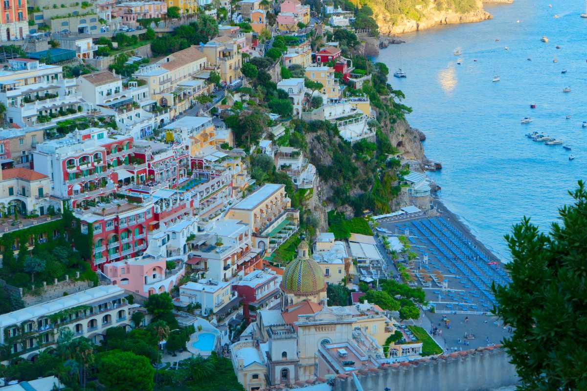 Panorama mattutino di Positano visto dall’alto, con le torri saracene in primo piano, il mare sullo sfondo e dettagli della natura mediterranea