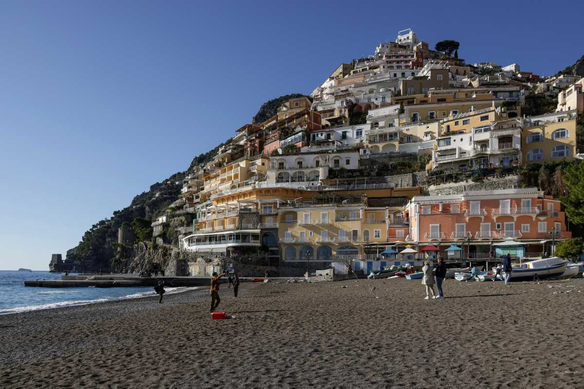 Vista panoramica dall'alto di Positano al tramonto, con le case colorate, la Spiaggia Grande e il mare, atmosfera vivace ma rilassante